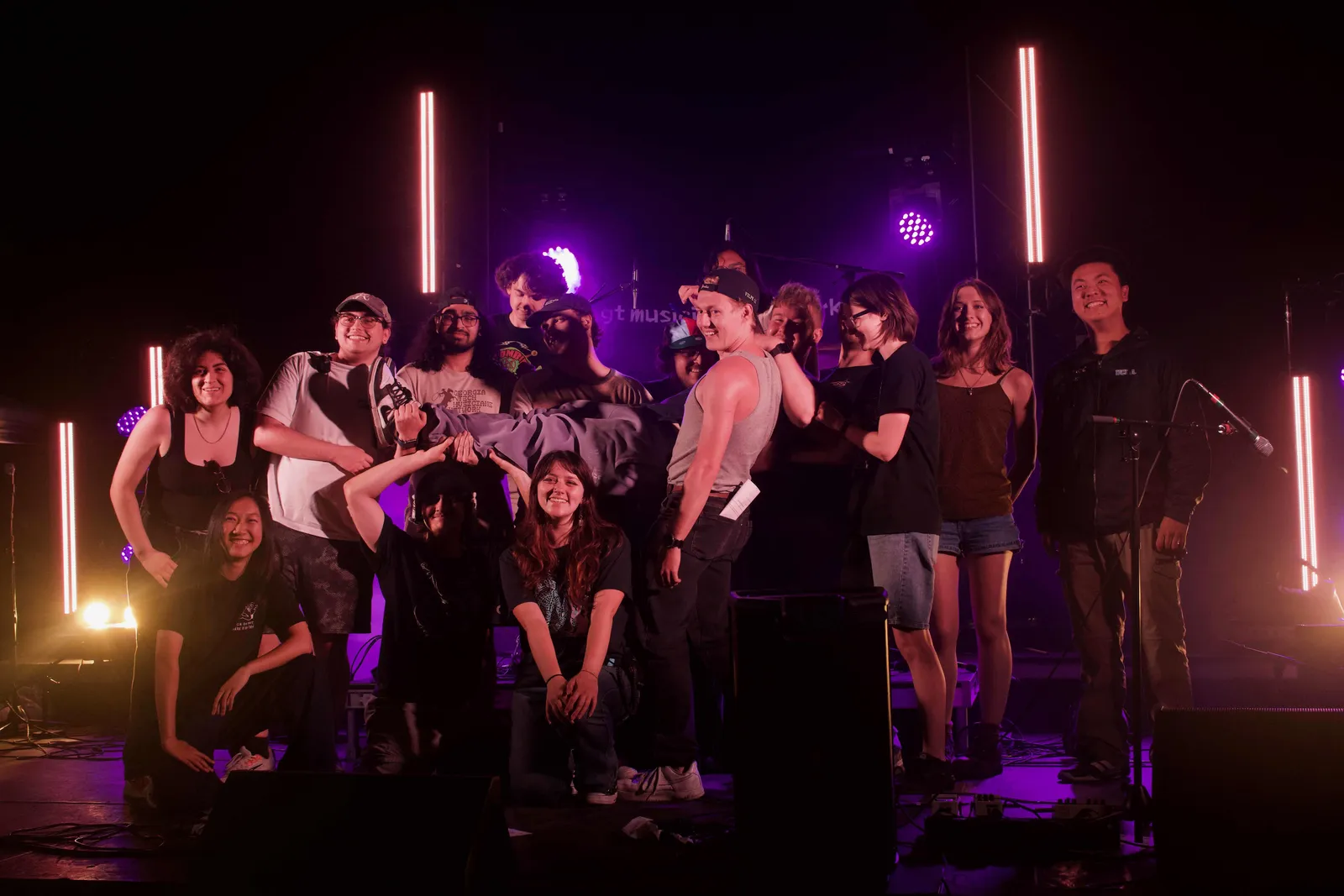 A larger WREK crew gathered outdoors at night between red stage light bars.