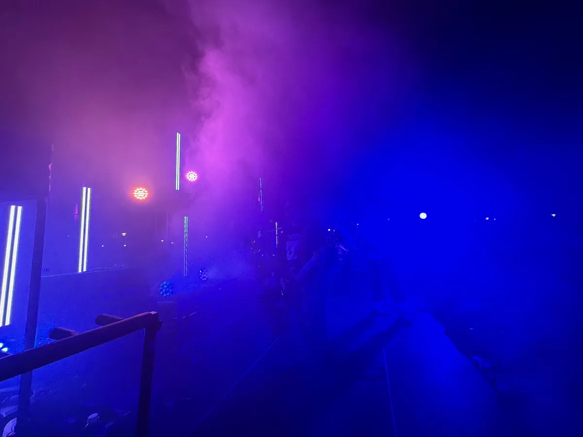 A stage lighting rig casting blue and purple haze over a performance space.
