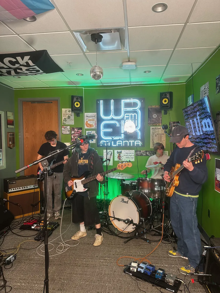 A band performing with microphones and a drum kit in the WREK studio.